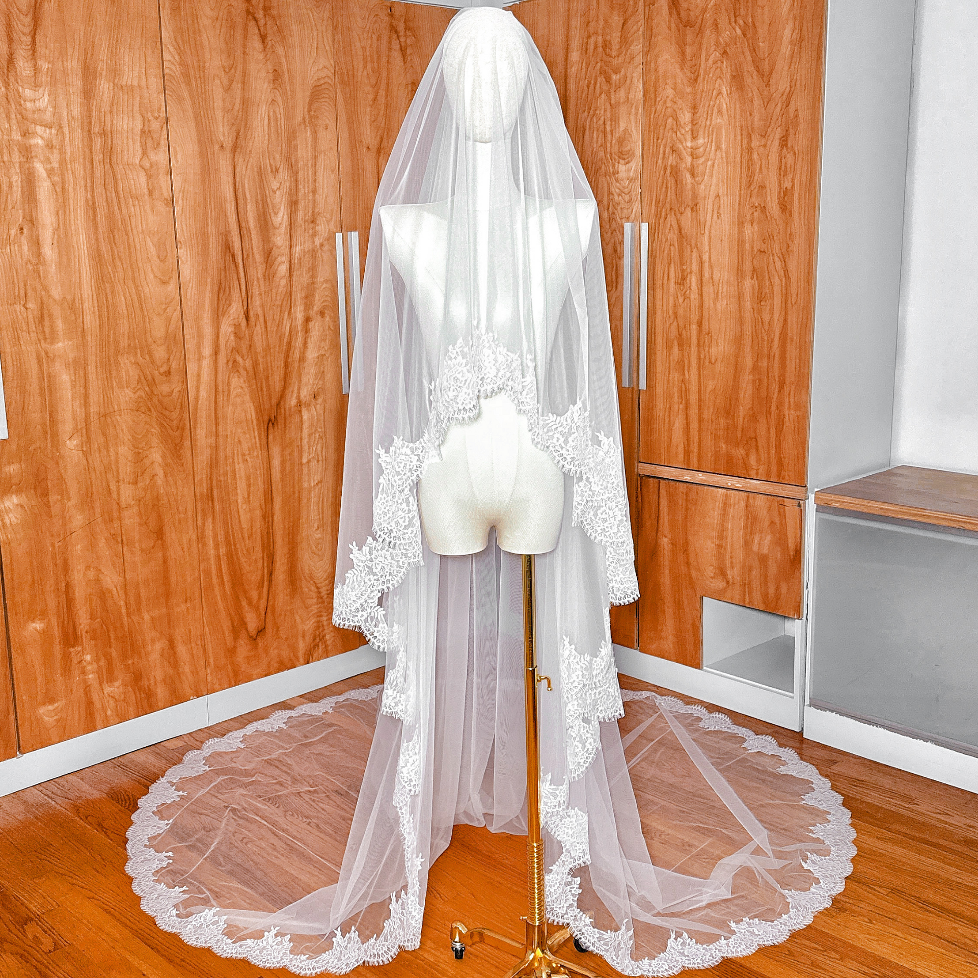 Front view of a two tier Chantilly lace veil in cathedral length displayed on a bridal mannequin, showing the delicate lace edging and blusher layer.