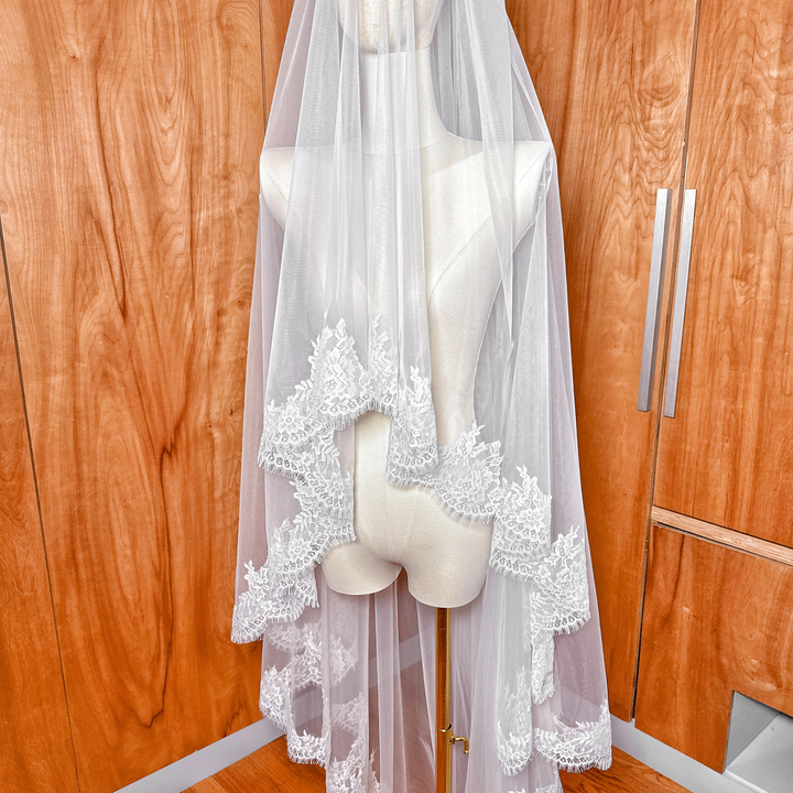 High-resolution image of the sheer tulle and soft Chantilly lace on a two tier cathedral length veil shown on a mannequin.