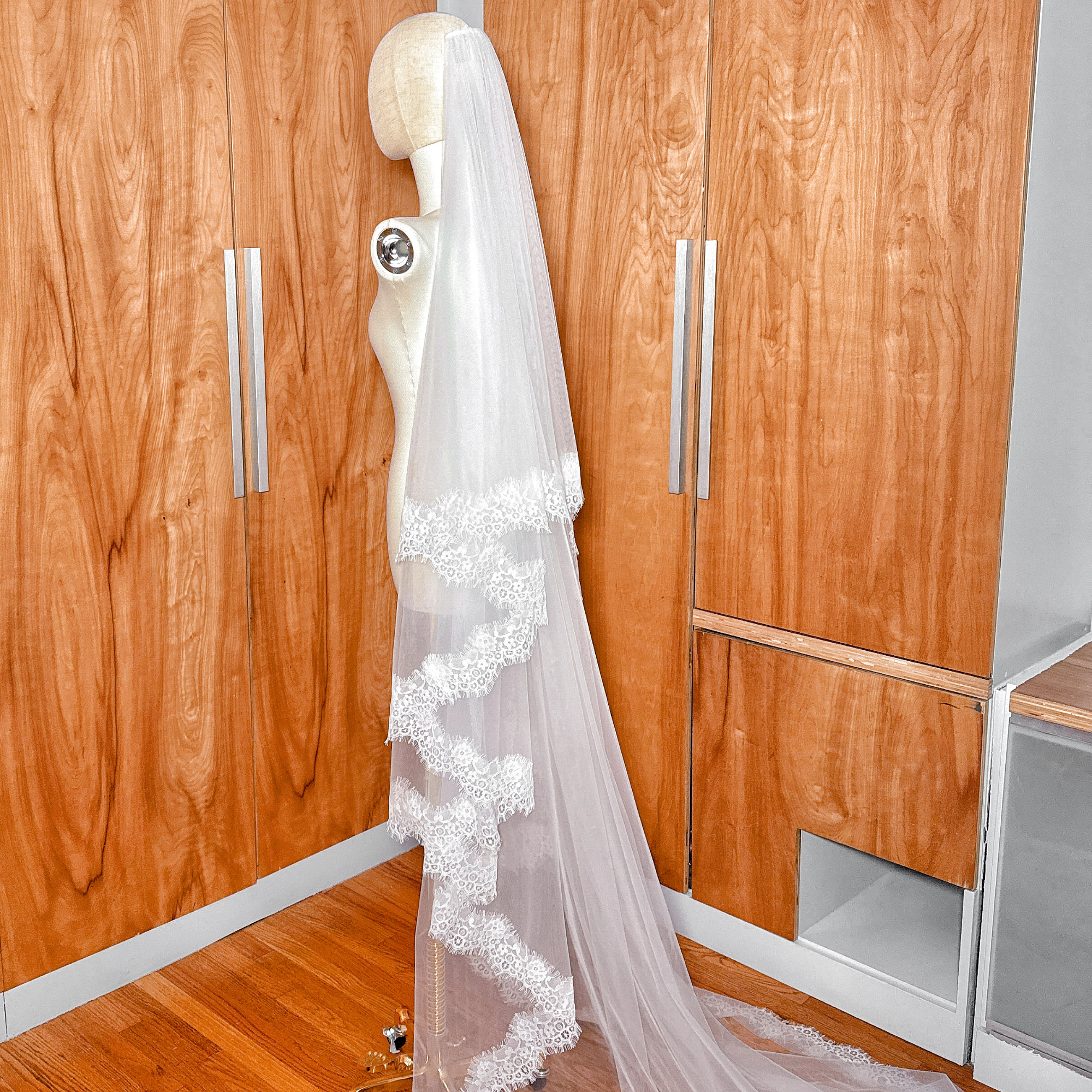 Cathedral length Two Tier Chantilly Lace Wedding Veil featuring a sheer blusher tier shown on a mannequin.