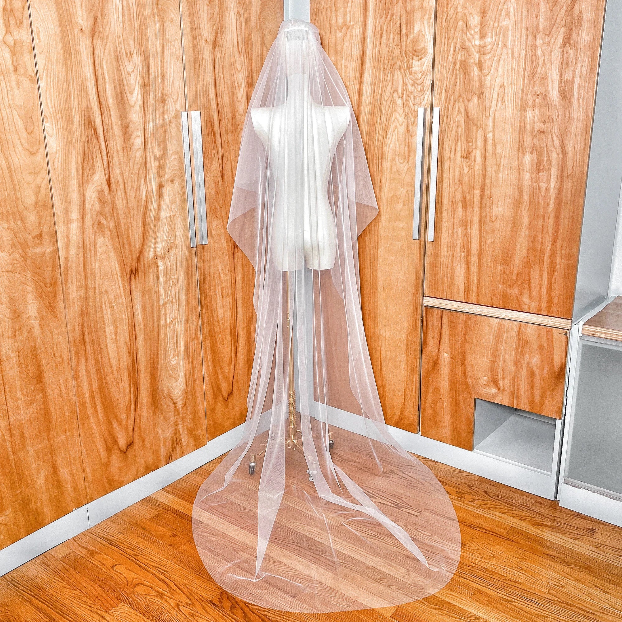 Back view of a two-tier chapel length bridal veil showing the long cathedral-style tier with a clean raw edge finish.