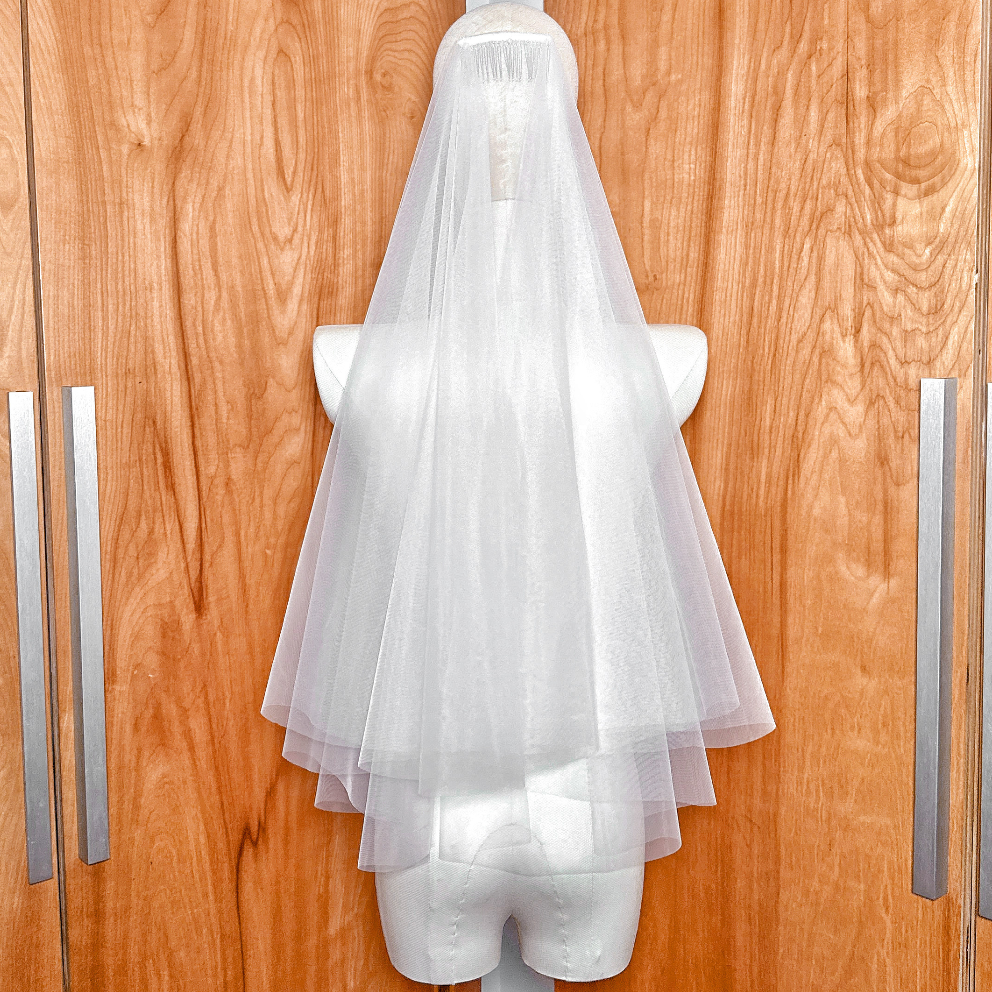Detailed view of the blusher layer on a two tier elbow length veil with a clean raw edge.