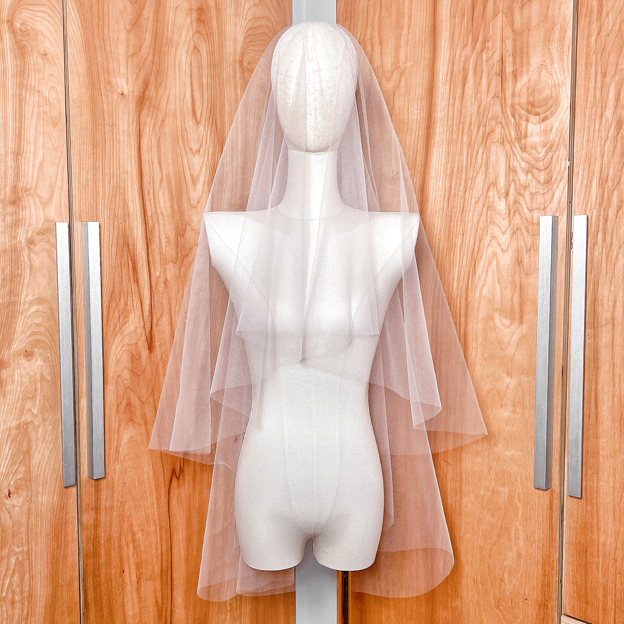 A two-tier fingertip length wedding veil with a clean raw edge and a blusher layer.
