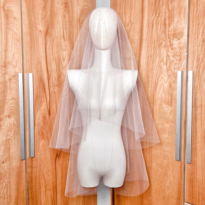 A two-tier fingertip length wedding veil with a clean raw edge and a blusher layer.