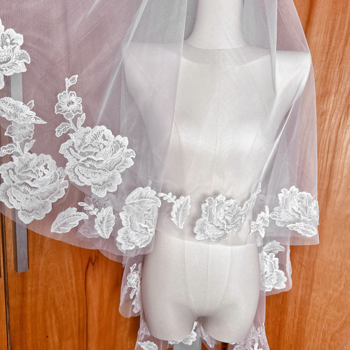 High-angle shot of a two tier floral lace wedding veil in fingertip length on a display mannequin.
