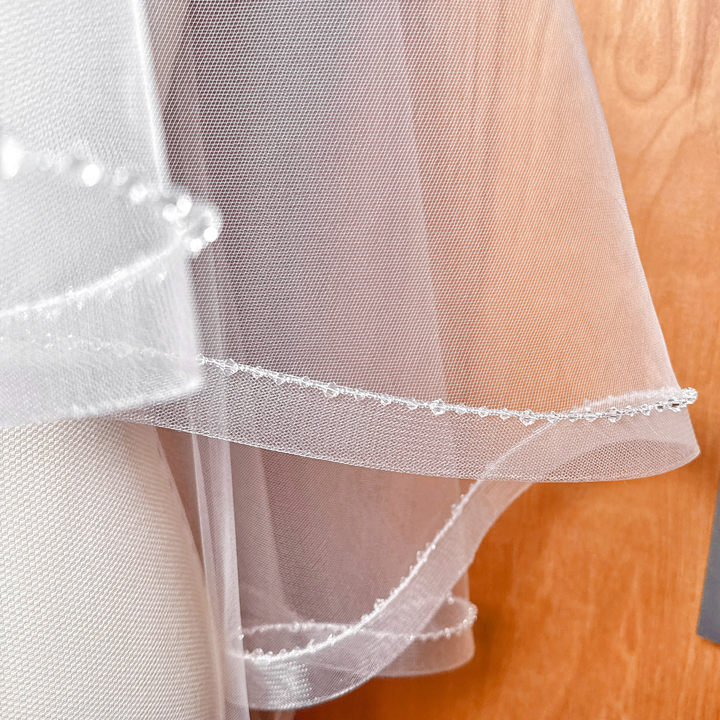 Side profile of a fingertip length two tier horsehair veil with crystal trim.