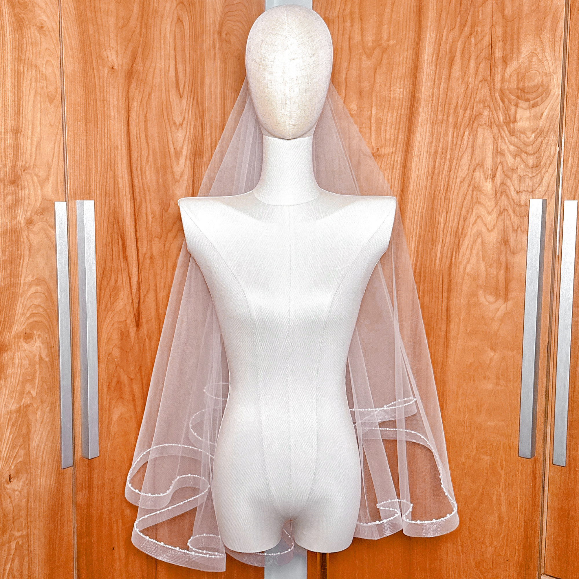 Luxurious fingertip length horsehair veil with double tiers and hand-placed pearl trim.