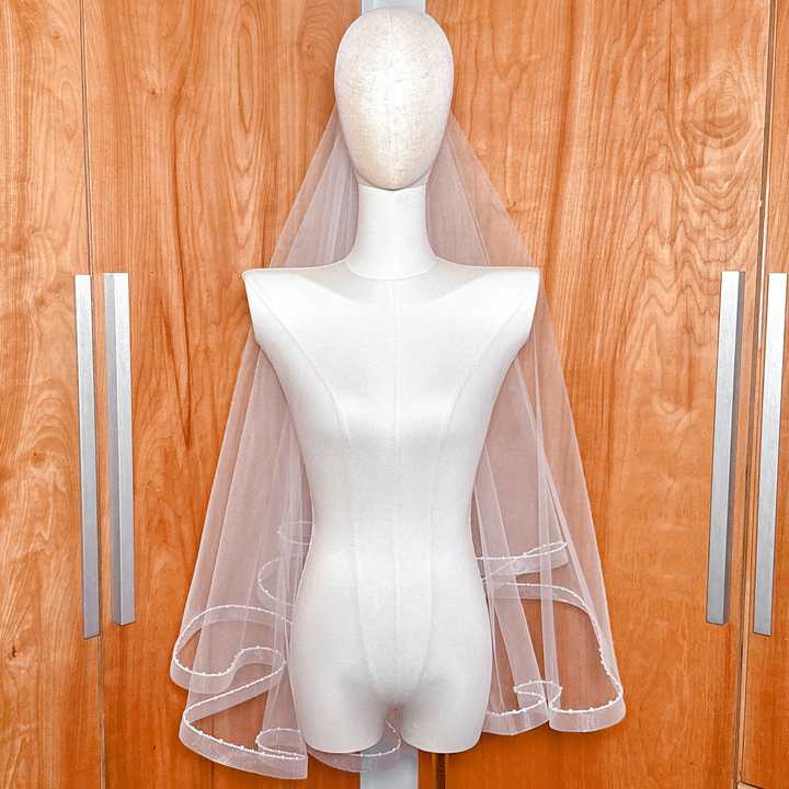 Luxurious fingertip length horsehair veil with double tiers and hand-placed pearl trim.