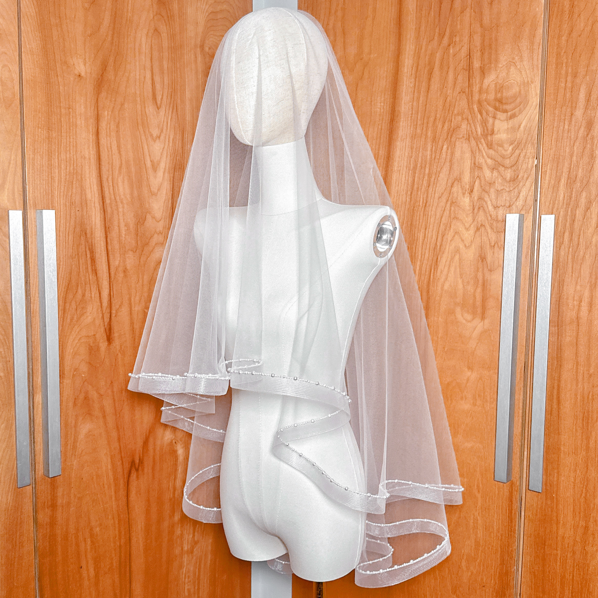 Elegant fingertip length version of the two-tier horsehair veil with decorative pearl trim.