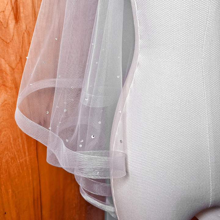 Detailed texture of the horsehair edge and scattered crystals on a two tier wedding veil.
