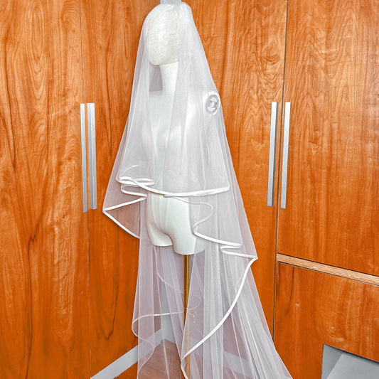 Close-up view of the clean ribbon edge detailing on a two tier cathedral length wedding veil with blusher.