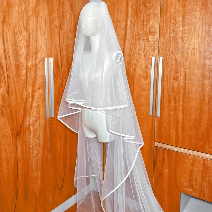 Close-up view of the clean ribbon edge detailing on a two tier cathedral length wedding veil with blusher.