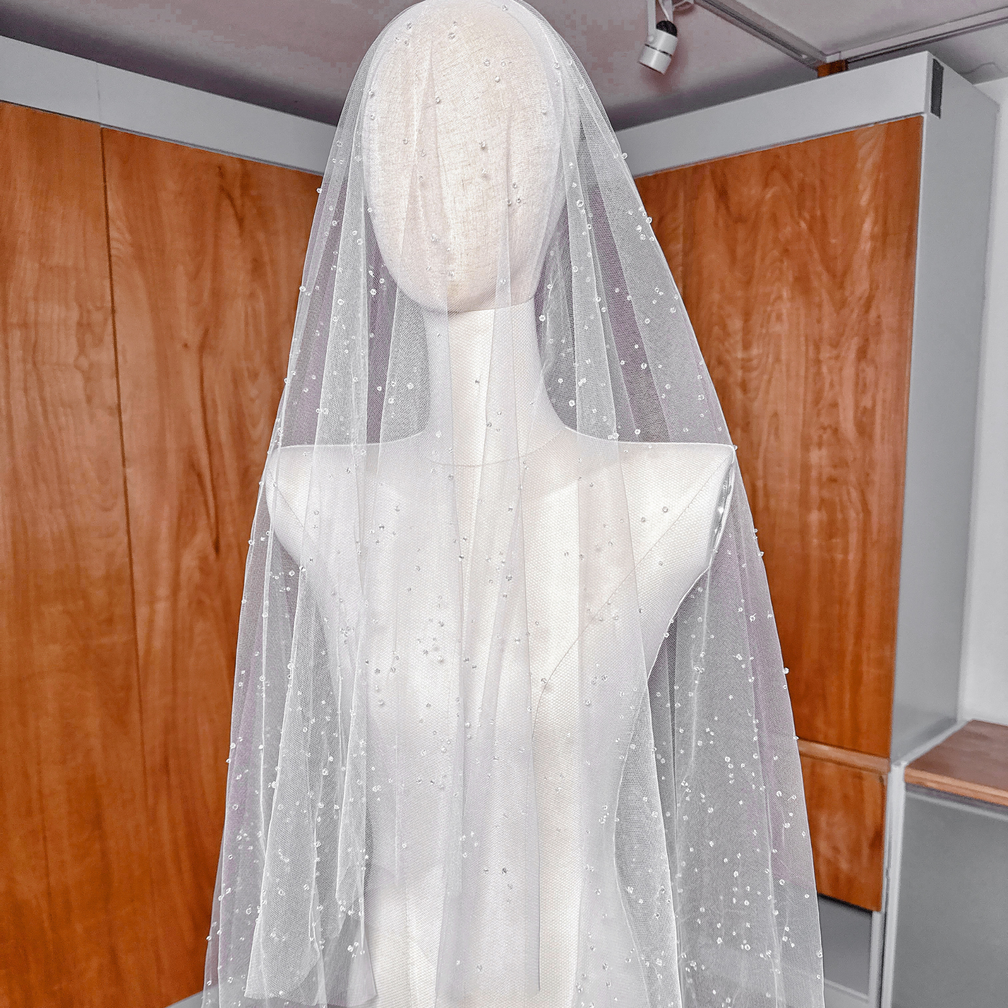 Two-tier scattered crystal beaded cathedral veil with the blusher layer pulled forward on a bridal mannequin.