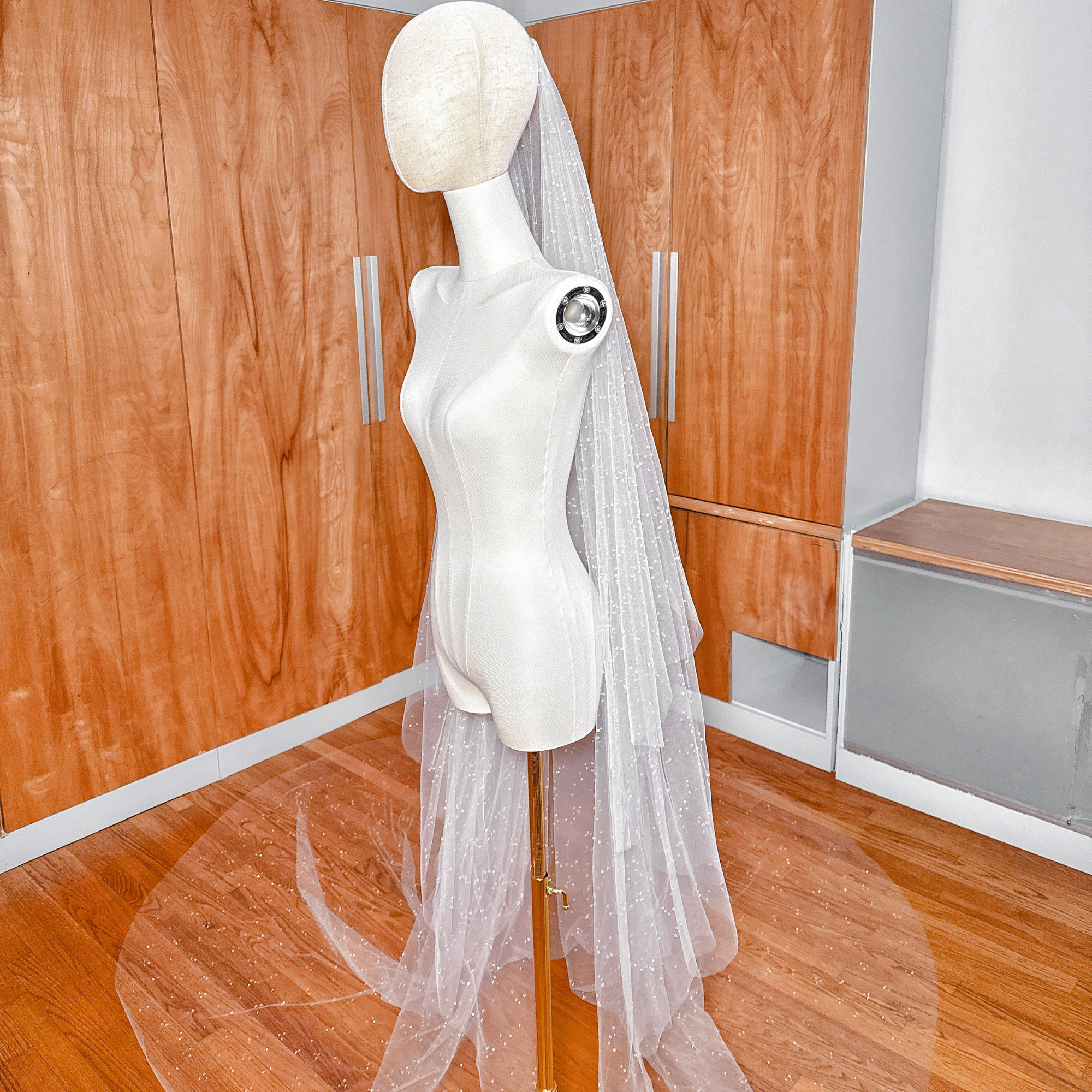 Two distinct layers of a scattered crystal beaded cathedral veil flowing behind a professional mannequin.