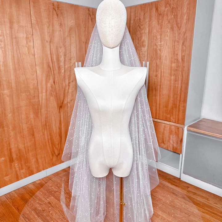 Wide shot of a bridal mannequin featuring a two-tier scattered crystal beaded cathedral length wedding veil.
