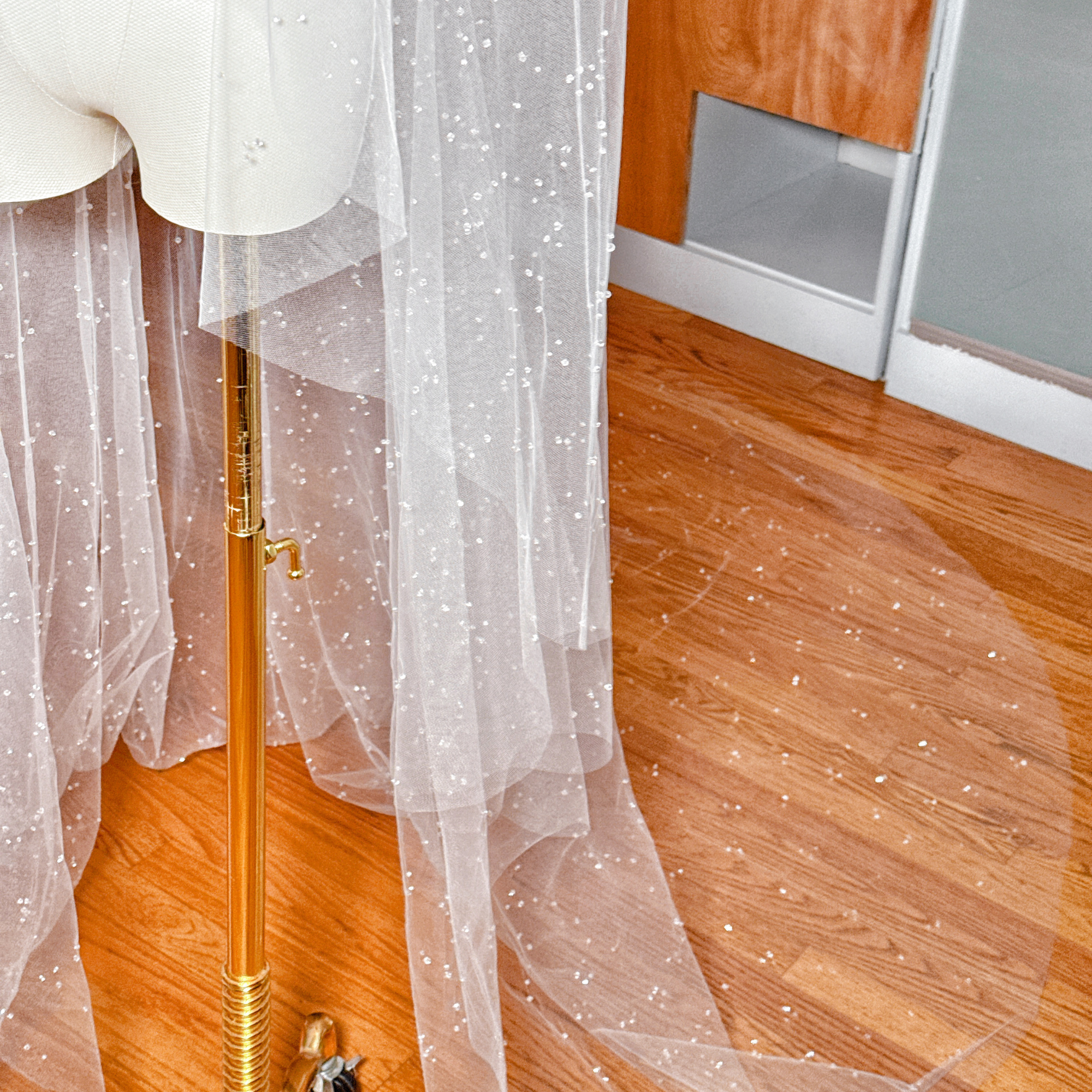 The flowing train of a two-tier scattered crystal beaded cathedral veil featuring a delicate sparkle throughout the tulle.