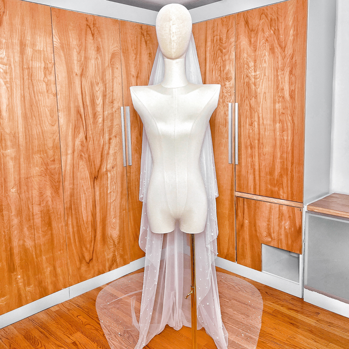 A two tier scattered pearl wedding veil in cathedral length draped over a mannequin to show the soft tulle detail.
