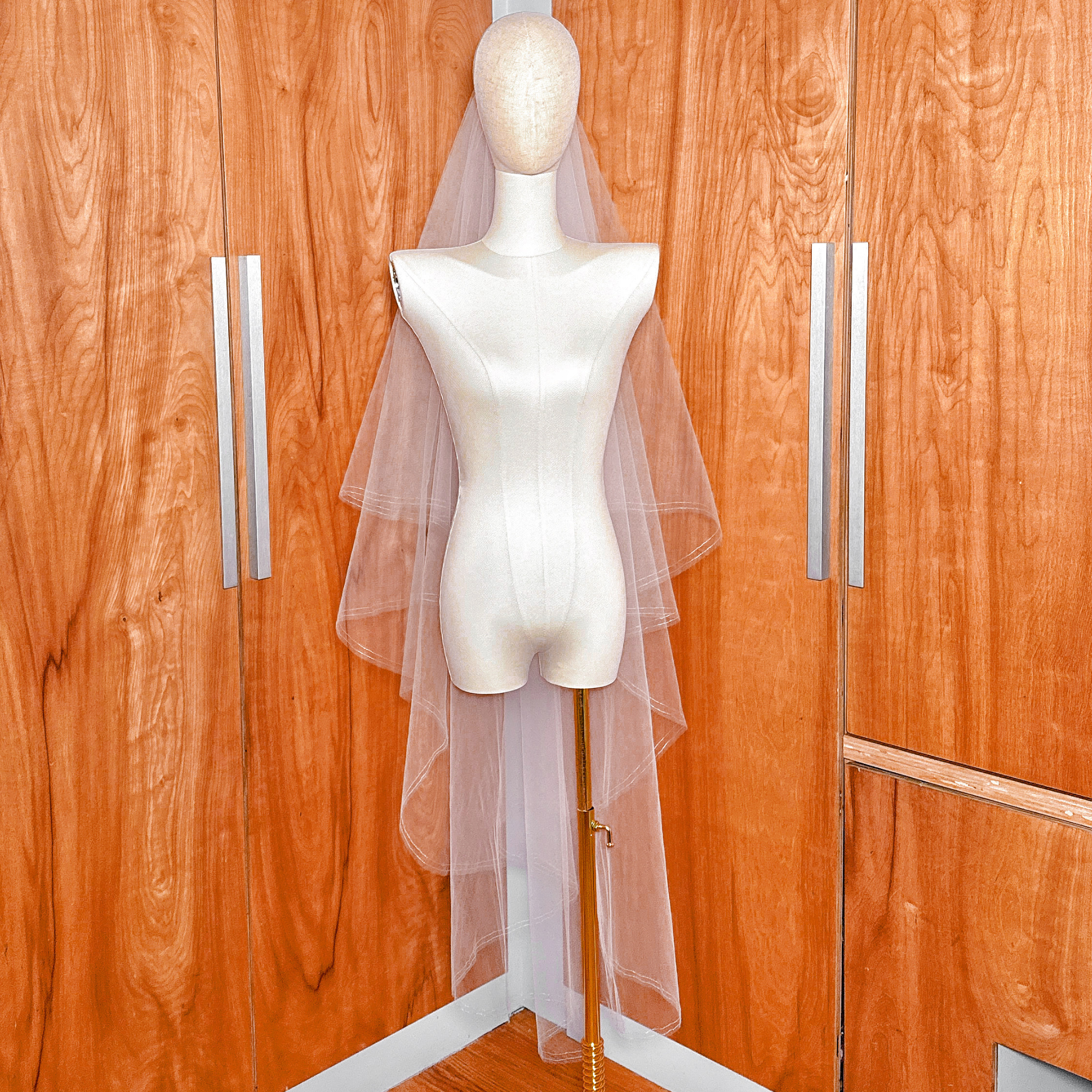Waltz length two tier veil featuring a front-facing blusher layer with a thin silver metallic border on a dress form.