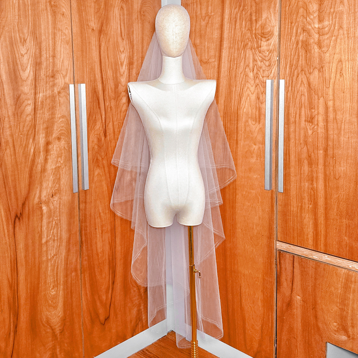 Waltz length two tier veil featuring a front-facing blusher layer with a thin silver metallic border on a dress form.