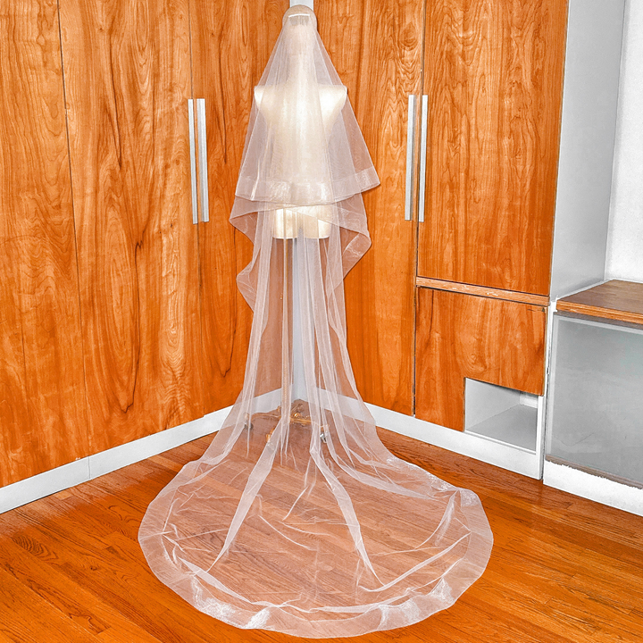 Full length view of a cathedral two tier wedding veil featuring a wide 3 inch horsehair trim and attached blusher.