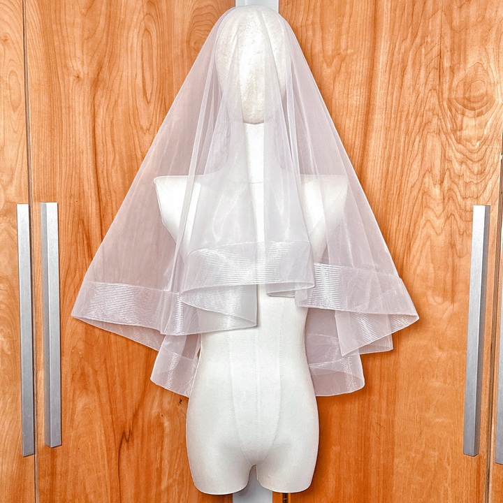 Elbow length two tier wedding veil featuring a 2 1/2 inch horsehair trim and blusher displayed on a mannequin.