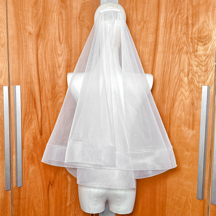 Mannequin display of a two tier wedding veil with horsehair trim and blusher shown in elbow length.