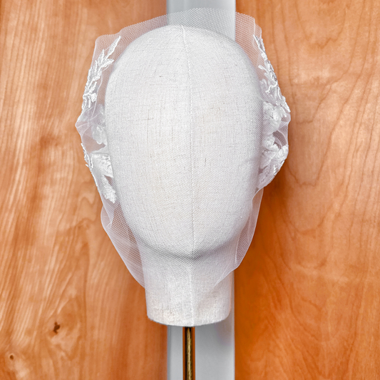 Front view of a vintage style lace birdcage wedding veil draped elegantly over the face.