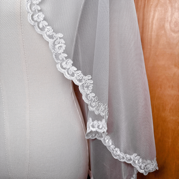Detailed close-up of intricate Alençon lace and corded floral patterns on a Juliet cap veil.