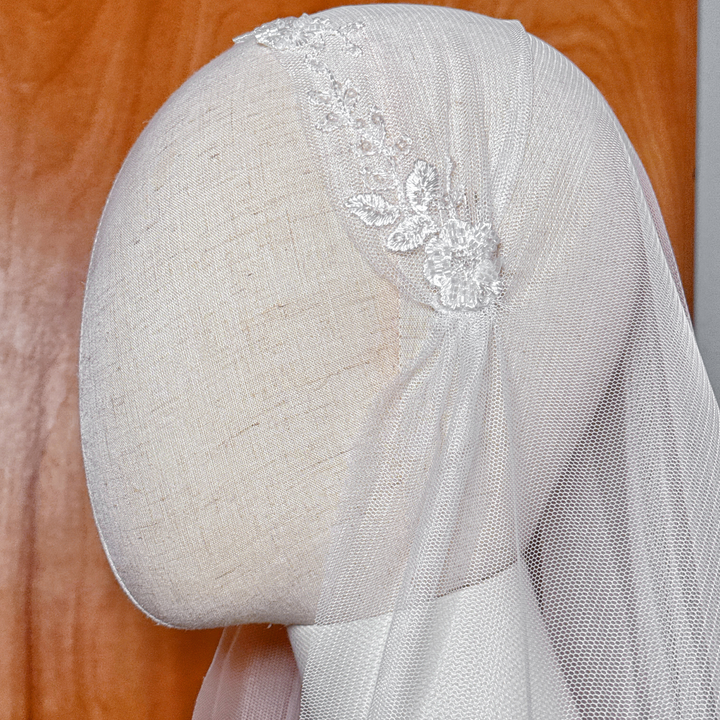 Detailed shot of the beaded lace pattern on the vintage style Juliet cap veil, emphasizing the shimmer and floral lace design.