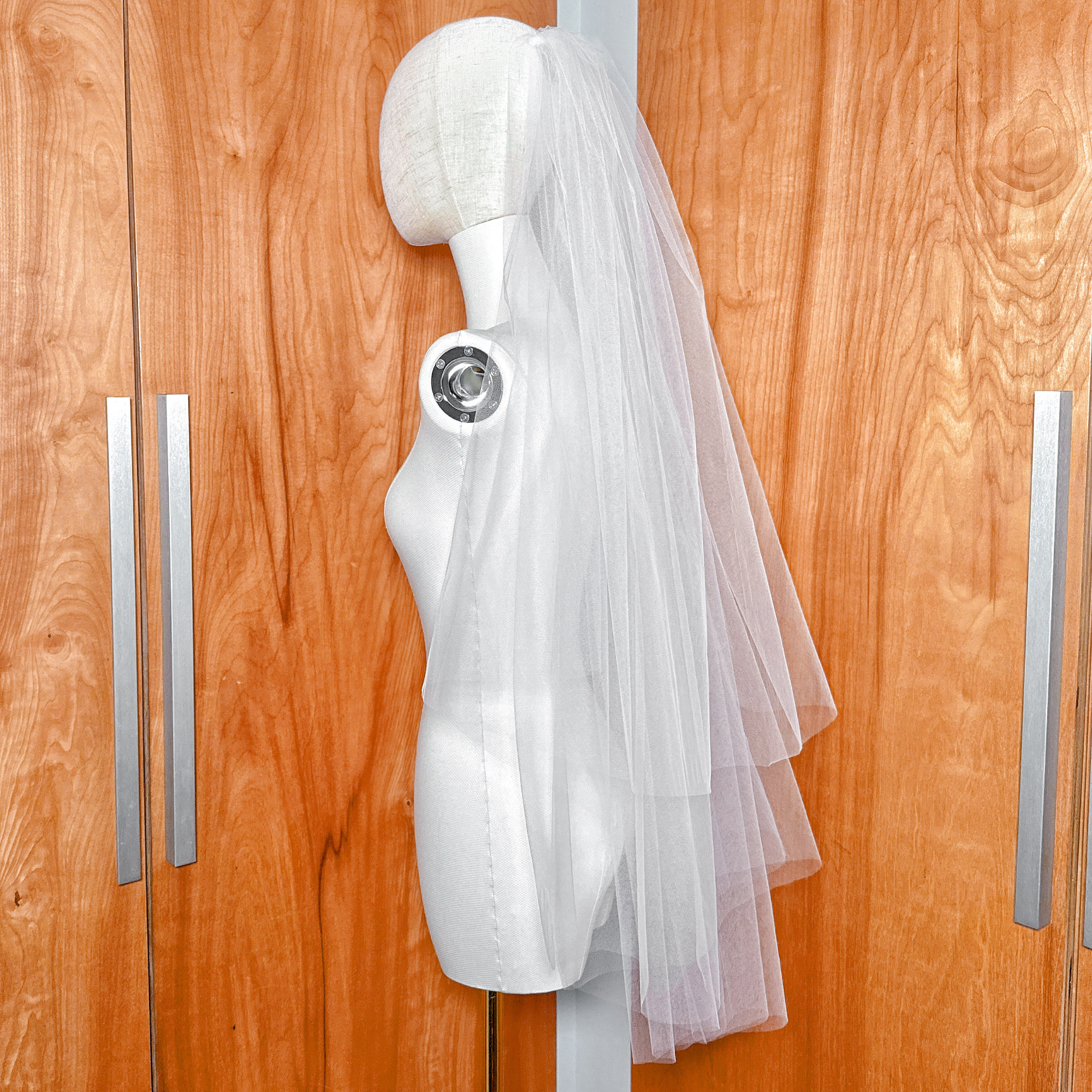 A voluminous two tier fingertip length blusher veil with both layers flipped back on a mannequin for maximum volume.