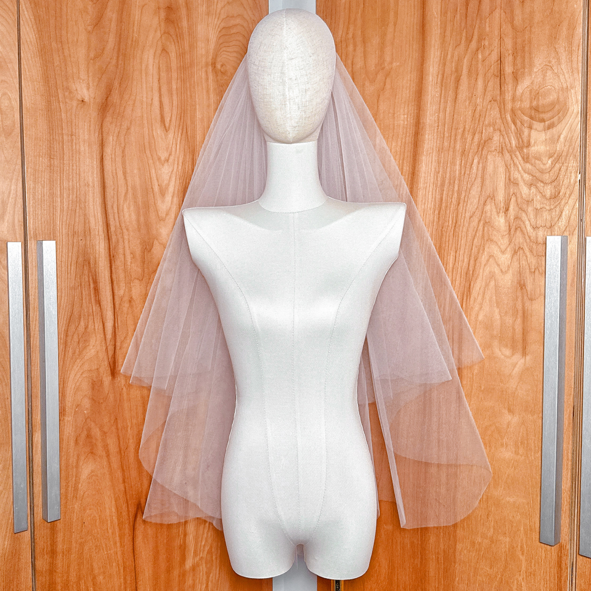 Front view of the fine bridal tulle on a voluminous two tier fingertip length blusher veil displayed on a mannequin.