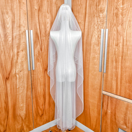 Back view showing the full drape and sheer fabric of a waltz length beaded edge wedding veil.