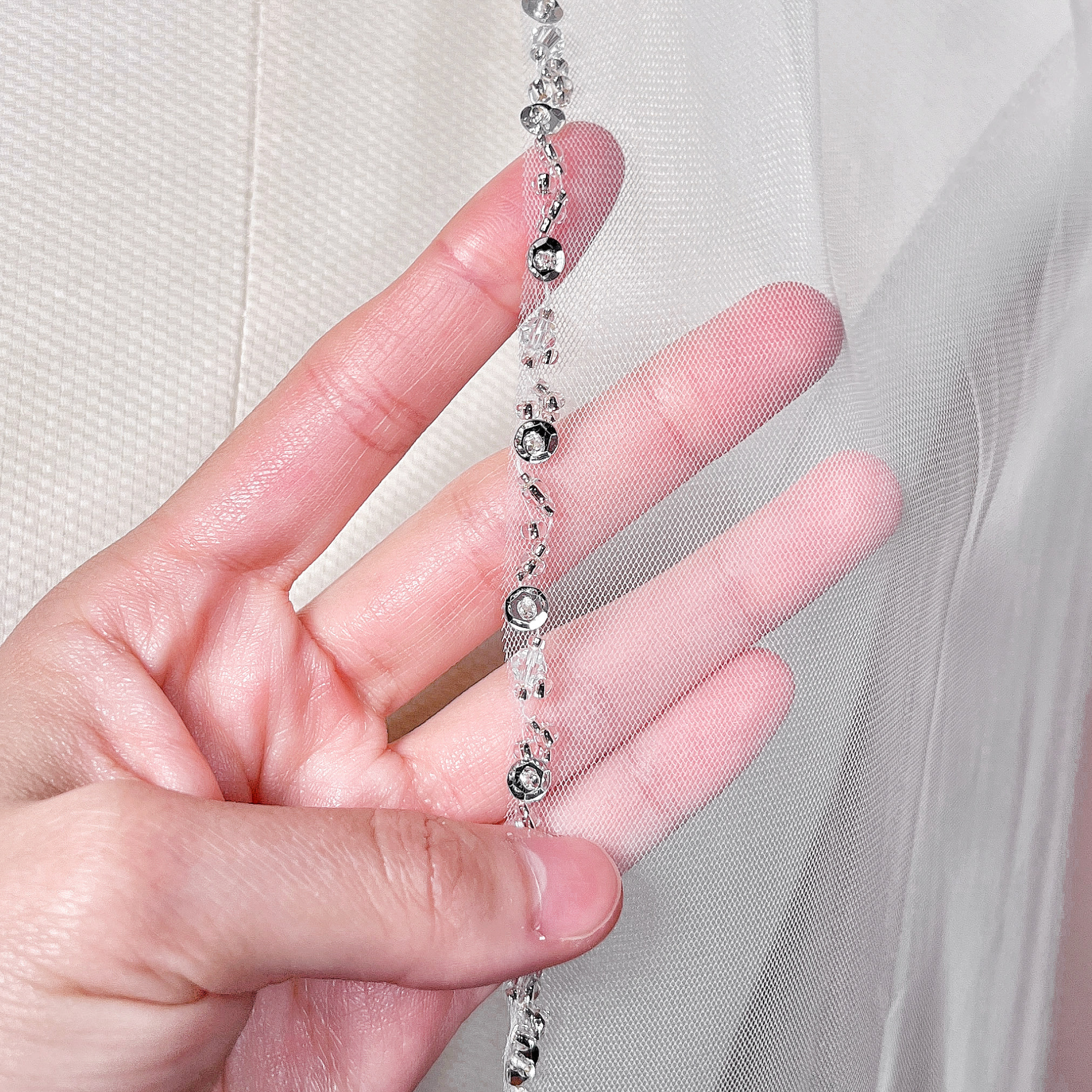 Close-up of a beaded edge wedding veil in waltz length on a display form.