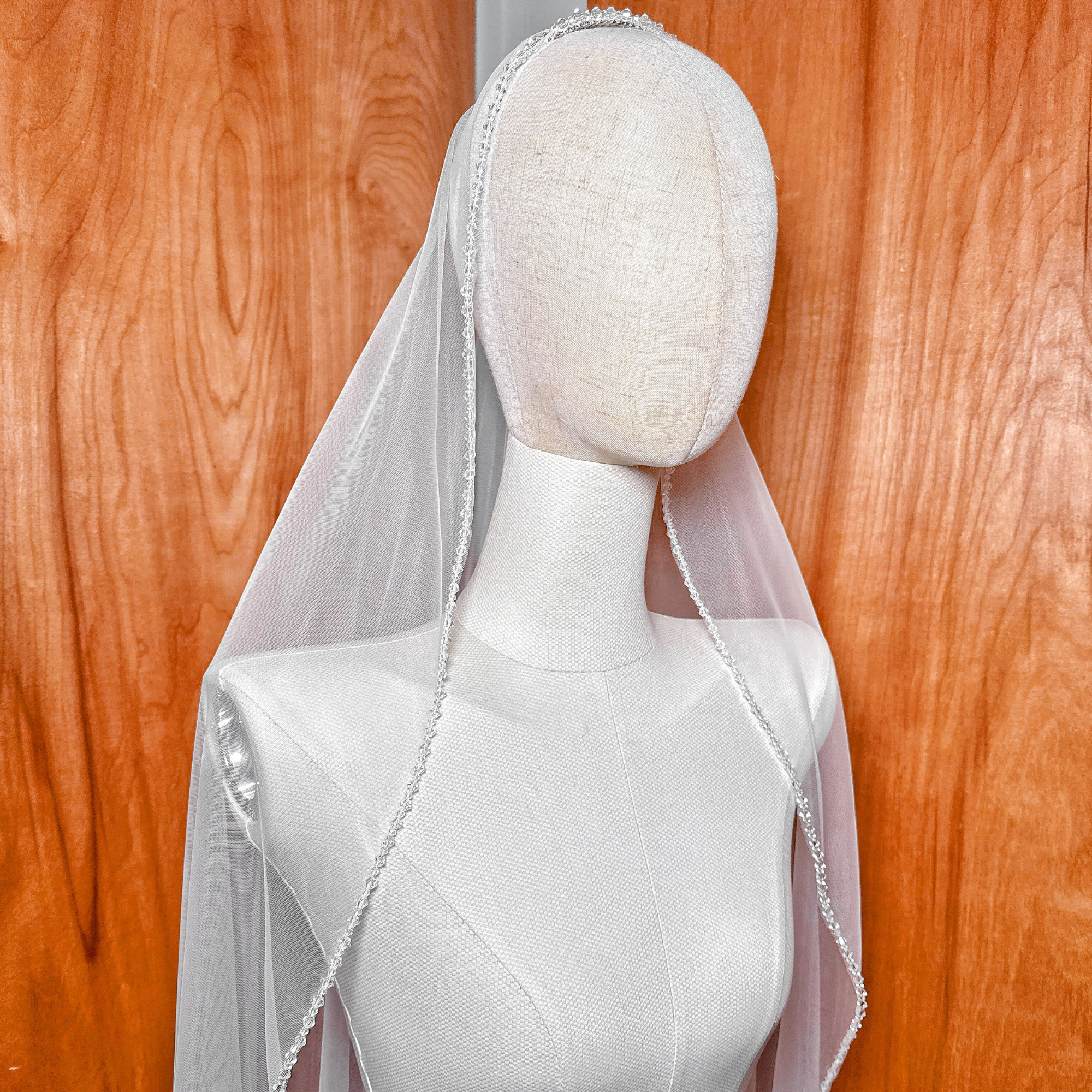 A waltz length crystal mantilla wedding veil draped elegantly over a bridal mannequin.