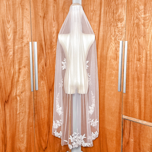 Back view of a waltz length wedding veil with white floral appliques displayed on a bridal mannequin.