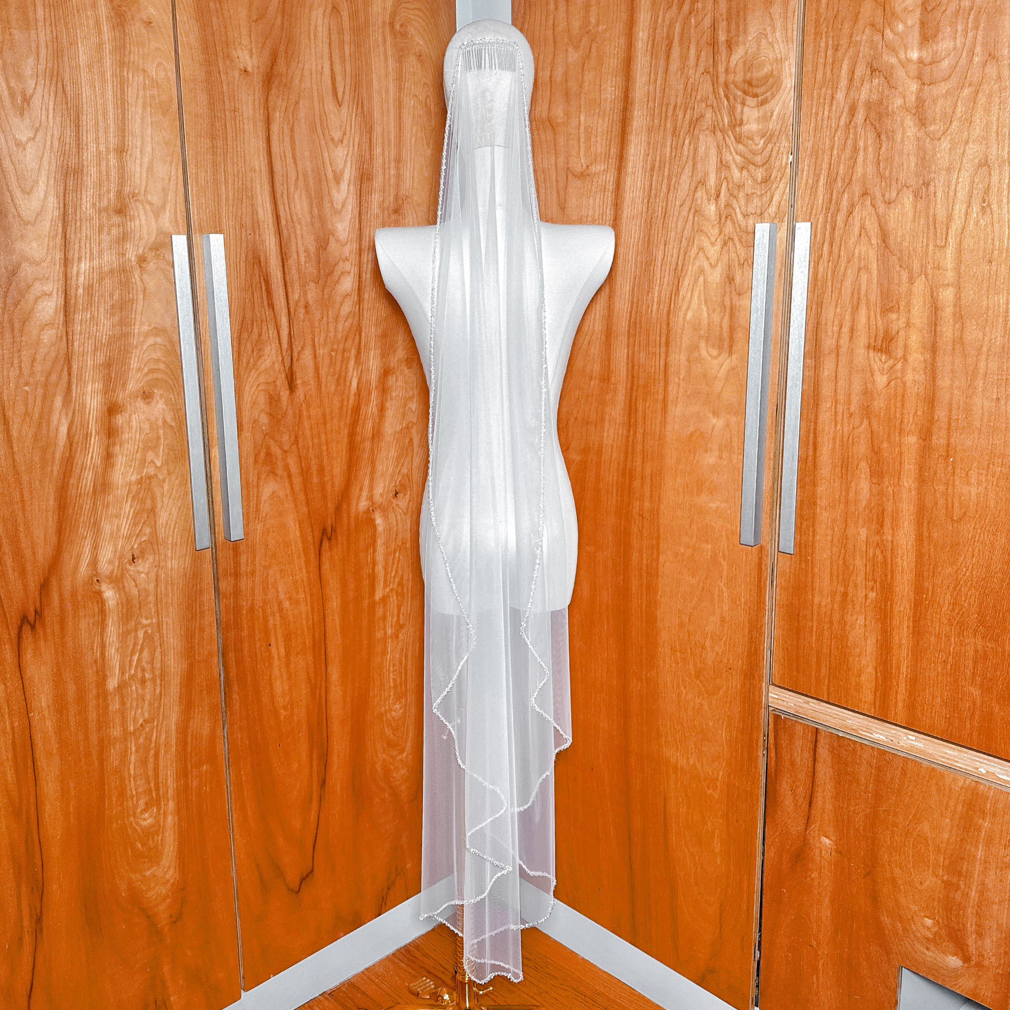 Full-length view of the crystal mantilla wedding veil falling to waltz length on a bridal form.
