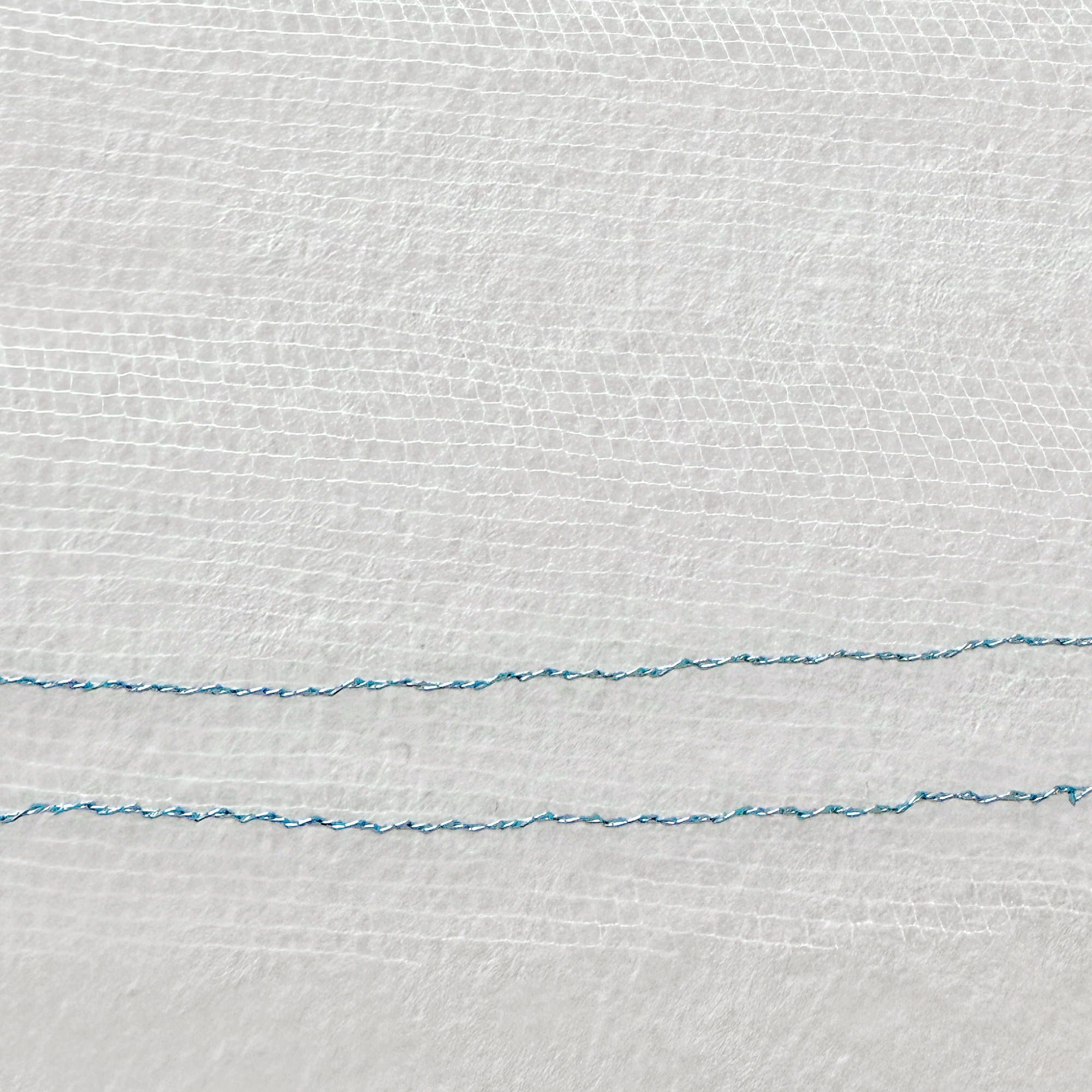 Close-up detail of the fine tulle and shiny blue metallic edge on a two tier wedding veil with blusher.