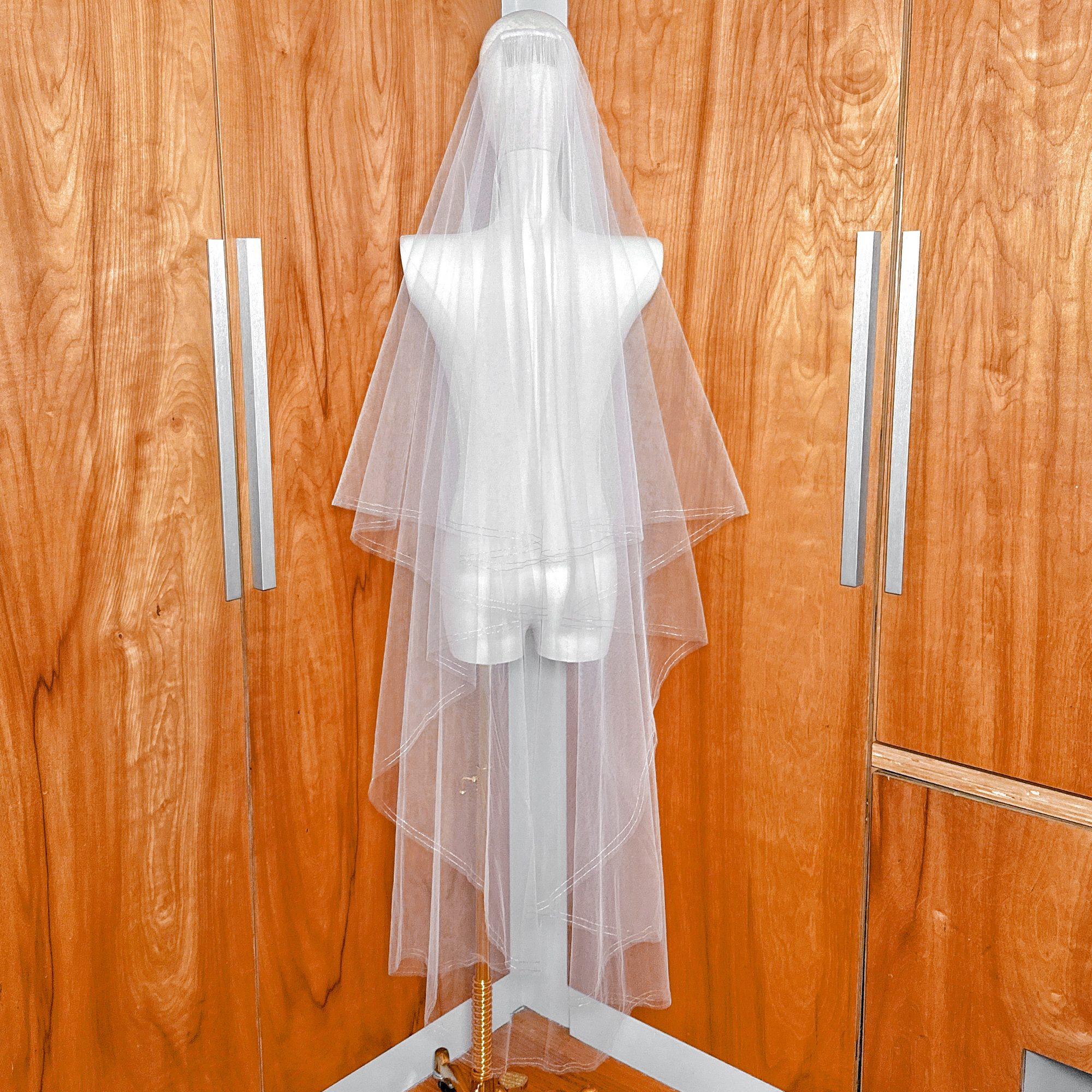 Back view of a waltz length two tier wedding veil with rose gold metallic edge cascading down.