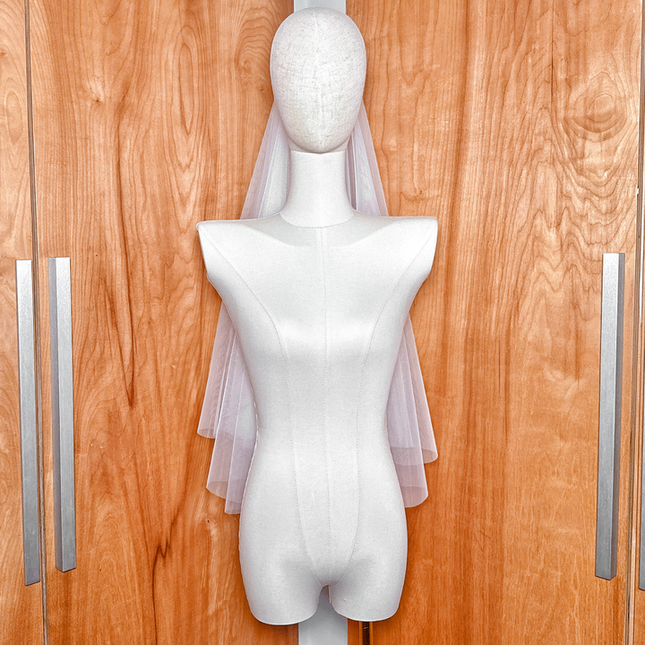 Two tier elbow length veil with a raw edge and blusher displayed to show the sheer drape and length.