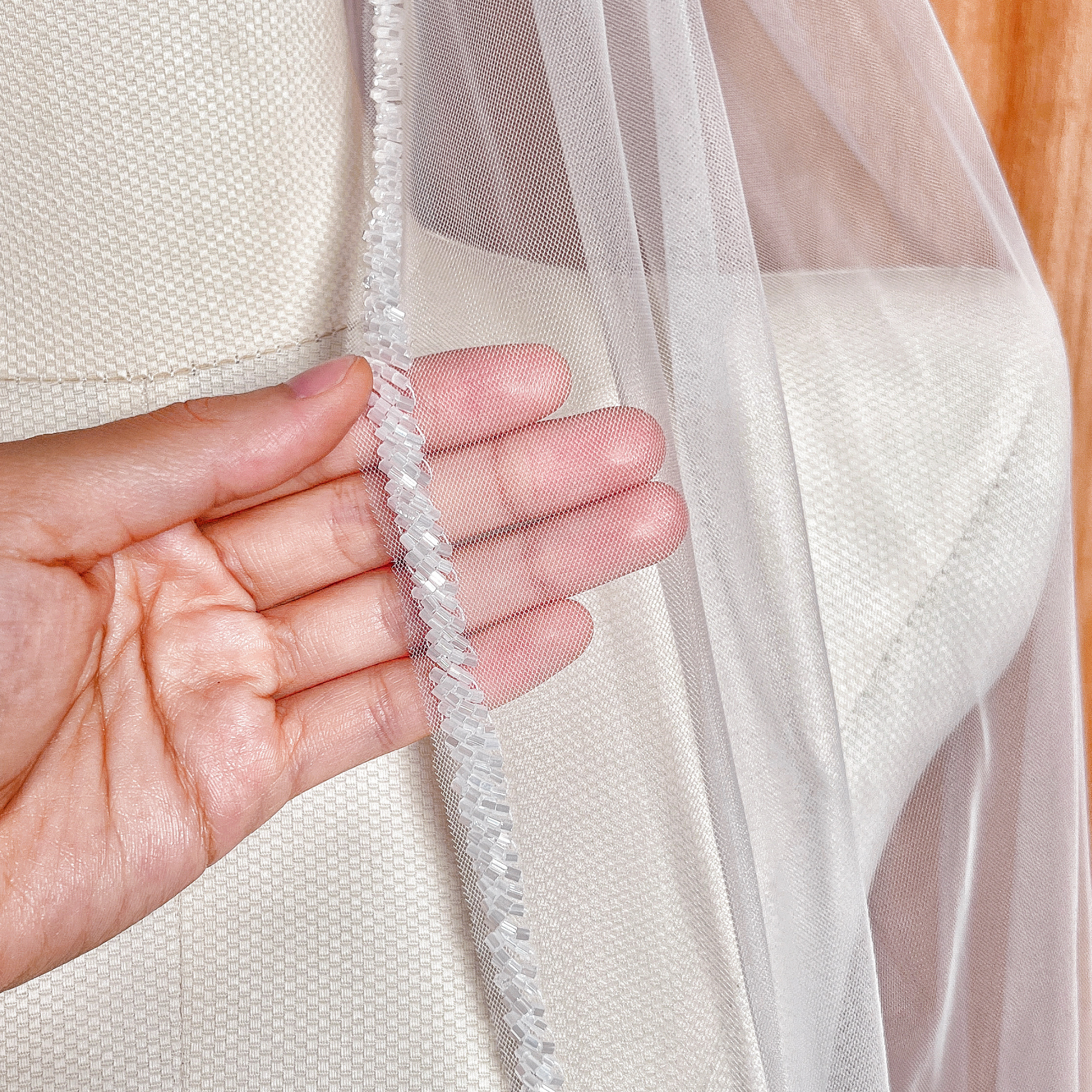 Close-up of frosted bugle beads on a beaded edge wedding veil in fingertip length.