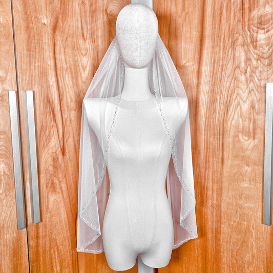 Front view highlighting the sheer tulle and pearl and crystal beaded edge of a fingertip wedding veil.