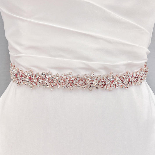 Front view of a wide beaded bridal belt with intricate crystal rhinestones in rose gold color on a bridal gown.