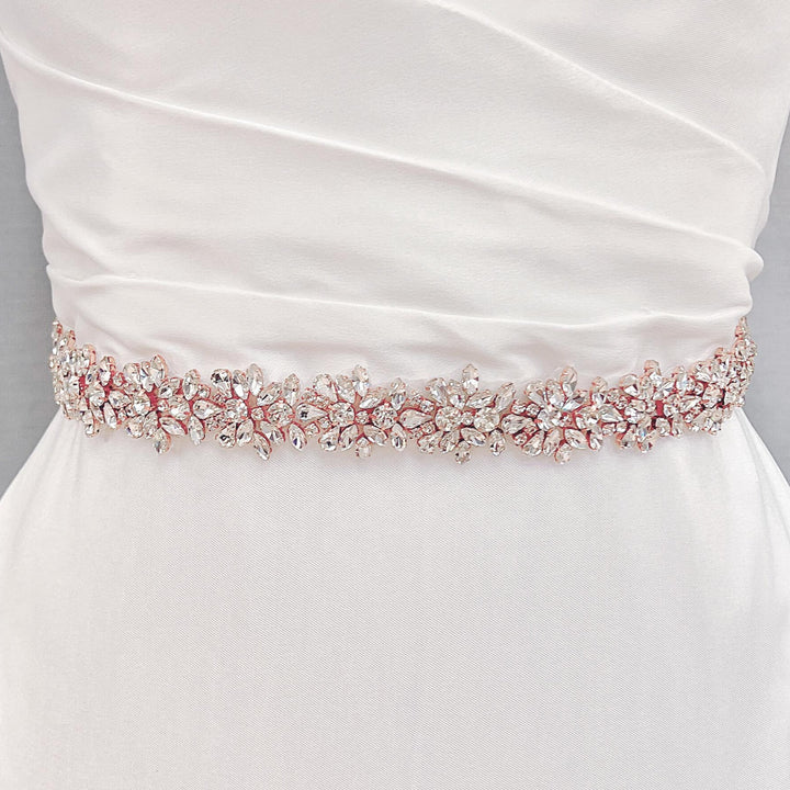 Front view of a wide beaded bridal belt with intricate crystal rhinestones in rose gold color on a bridal gown.