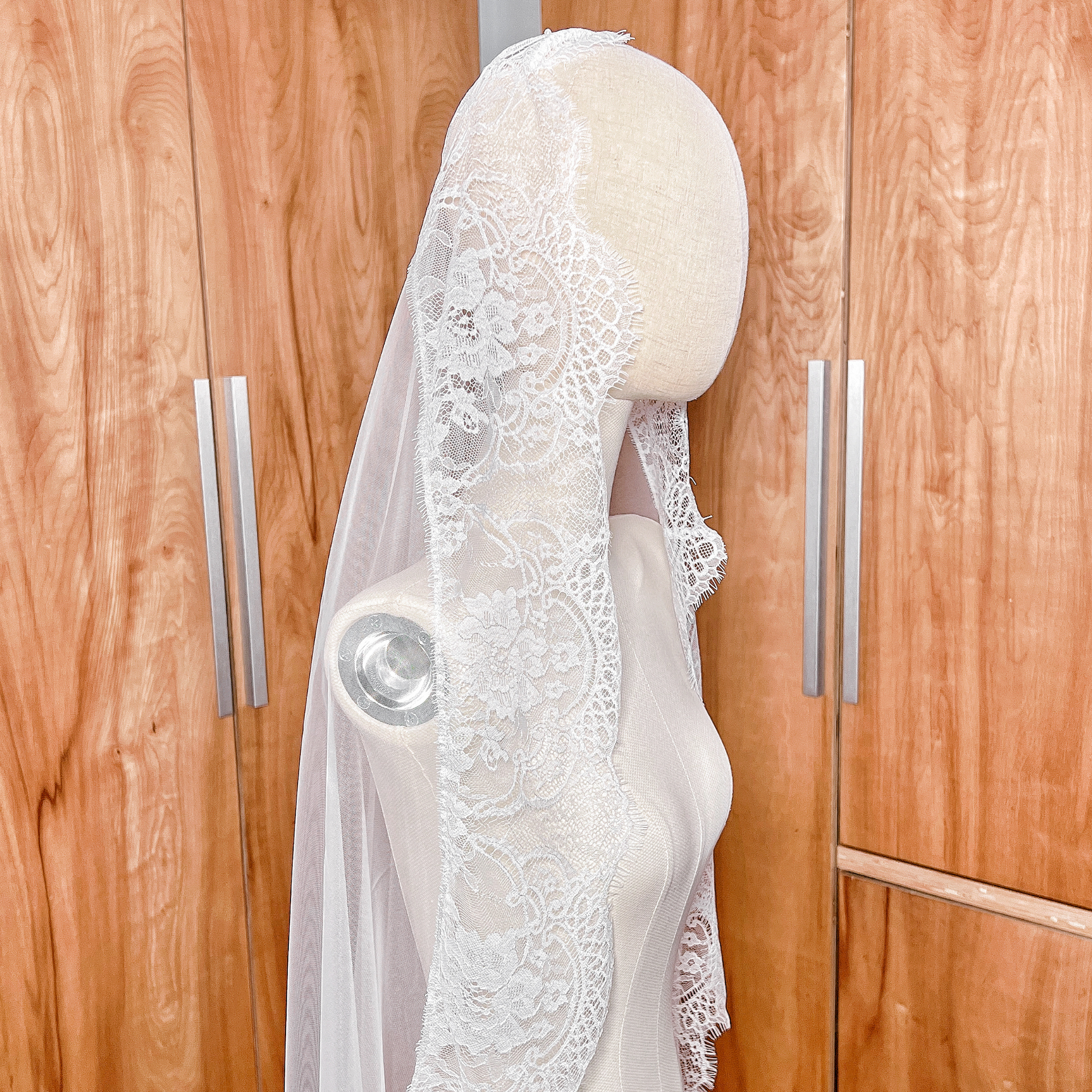 Detailed close-up of the delicate floral eyelash lace on the Wide Chantilly Lace Bridal Mantilla Veil, shown on a bridal mannequin.