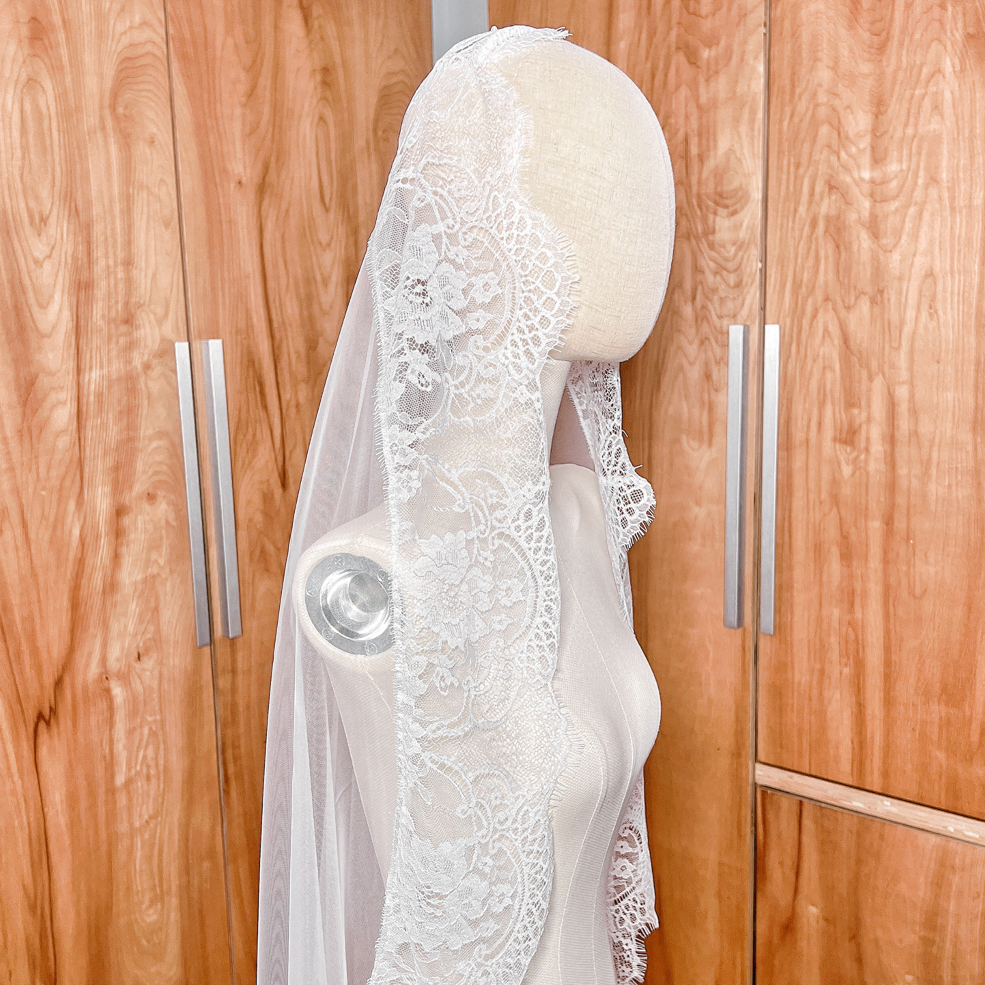 Detailed close-up of the delicate floral eyelash lace on the Wide Chantilly Lace Bridal Mantilla Veil, shown on a bridal mannequin.