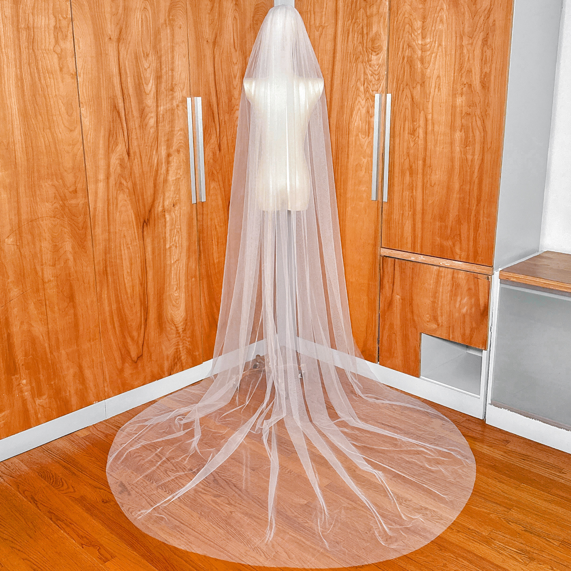 Back view showing the long, dramatic drape of the wide raw edge cathedral length wedding veil.
