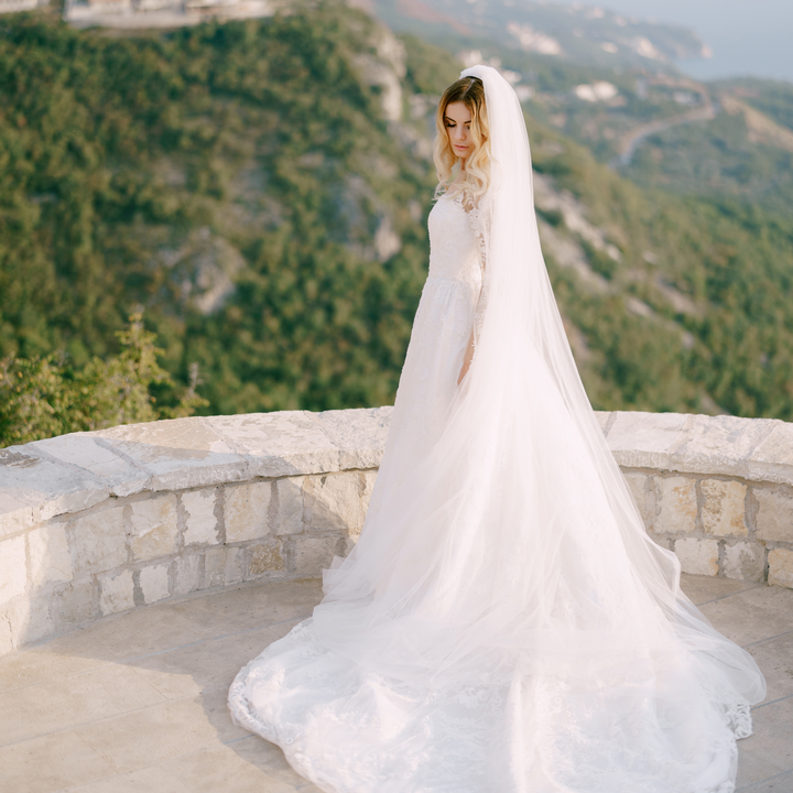 An overhead angle displaying the expansive spread and width of the cathedral wedding veil with raw edges.