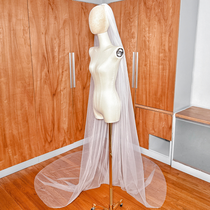 Side profile of the wide cathedral veil showing how the raw edge tulle falls softly away from the head.